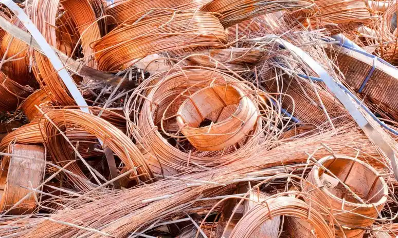 A pile of clean, coiled copper wire scrap ready for recycling at a scrap yard.