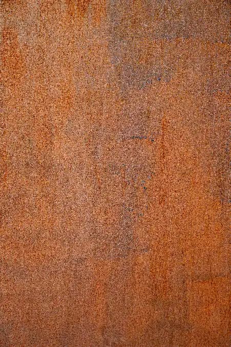 A close-up of a weathering steel surface showing the natural warm brown rust patina that forms as a protective layer on Corten steel over time.