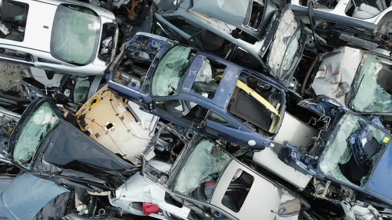 Aerial view of stripped and damaged car bodies stacked tightly together at a scrapyard.