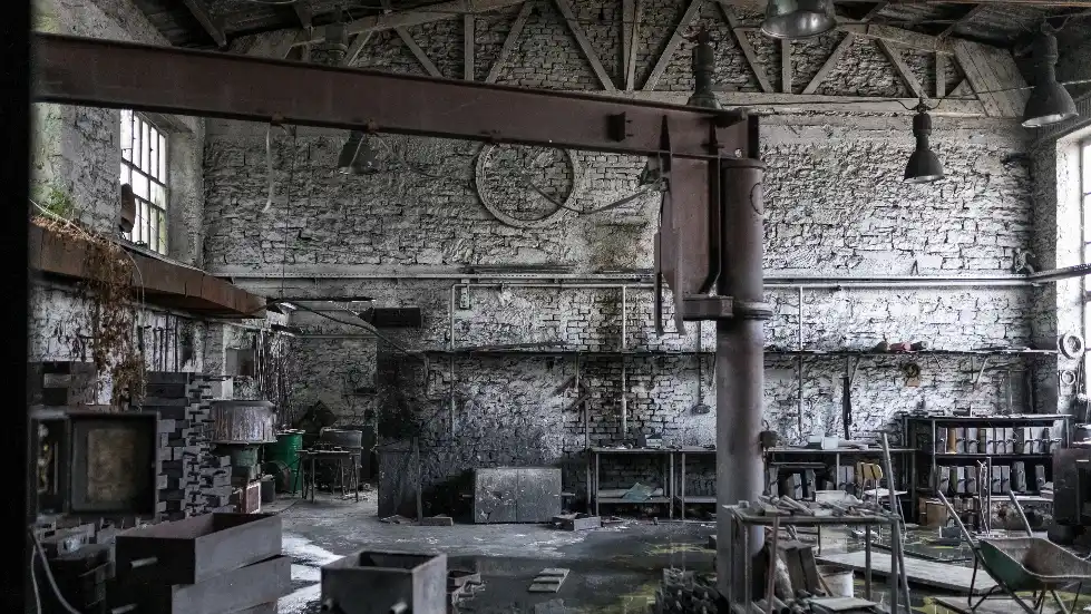 An old abandoned warehouse with rusty metal beams, shelves, pipes and equipment showing hidden scrap metal potential in unused spaces.